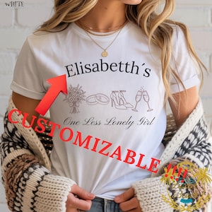 Op de afbeelding: Wit T-shirt met de tekst "Elisabetth's" boven een afbeelding van een boeket, ringen, hakken en champagneglazen. Daaronder staat de tekst "One Less Lonely Girl". Het woord "CUSTOMIZABLE" is in het rood gedrukt.