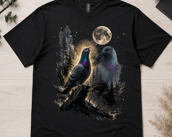 May include: A black t-shirt featuring a graphic print of a pigeon perched on a dark tree stump. The scene includes a full moon, a starry night sky, and a silhouette of a forest. The pigeon has iridescent purple and green neck feathers.