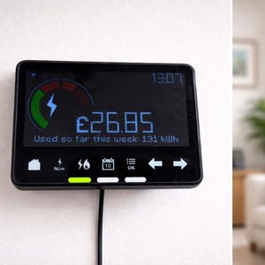 May include: A black smart meter displaying energy usage information. The screen shows a cost of $26.85, the time 13:07, and usage of 131 kWh. The meter is mounted on a white wall.