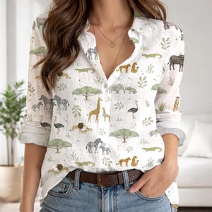 May include: A white long-sleeve button-down shirt featuring a repeating pattern of various African safari animals including zebras, giraffes, lions, elephants, and crocodiles, interspersed with green acacia trees and small leafy plant illustrations.