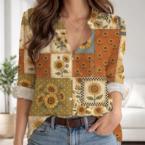 May include: A long-sleeved button-down shirt with a patchwork design featuring sunflowers in various squares. The shirt has a V-neck and rolled-up sleeves. The color palette includes shades of yellow, orange, green, and blue.