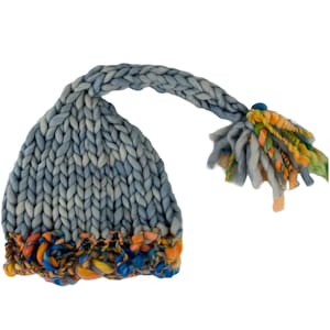 Peut inclure: Un bonnet en tricot bleu en forme de lutin avec une longue queue et des accents de fil coloré. Le bonnet est fait avec un fil épais et a une coupe ample et décontractée.  PDF Knitting Pattern Cute Pixie Hat for a New Baby by Knitting Times Design.