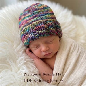 May include: A colorful, hand-knitted beanie hat in shades of purple, blue, green, and yellow. The hat is worn by a newborn baby wrapped in a cream-colored blanket. Text on the image reads "Newborn Beanie Hat: PDF Knitting Pattern."
