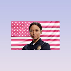 May include: A woman in a dark blue uniform with a badge, arms crossed, against a pink and white American flag background. The flag features pink stripes and white stars.