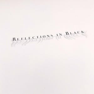 Puede incluir: Superficie blanca con el texto "REFLECTIONS IN BLACK" impreso en una fuente fina y elegante. El texto proyecta una sombra, a&ntilde;adiendo profundidad. Un borde de madera oscura es visible en la parte superior.