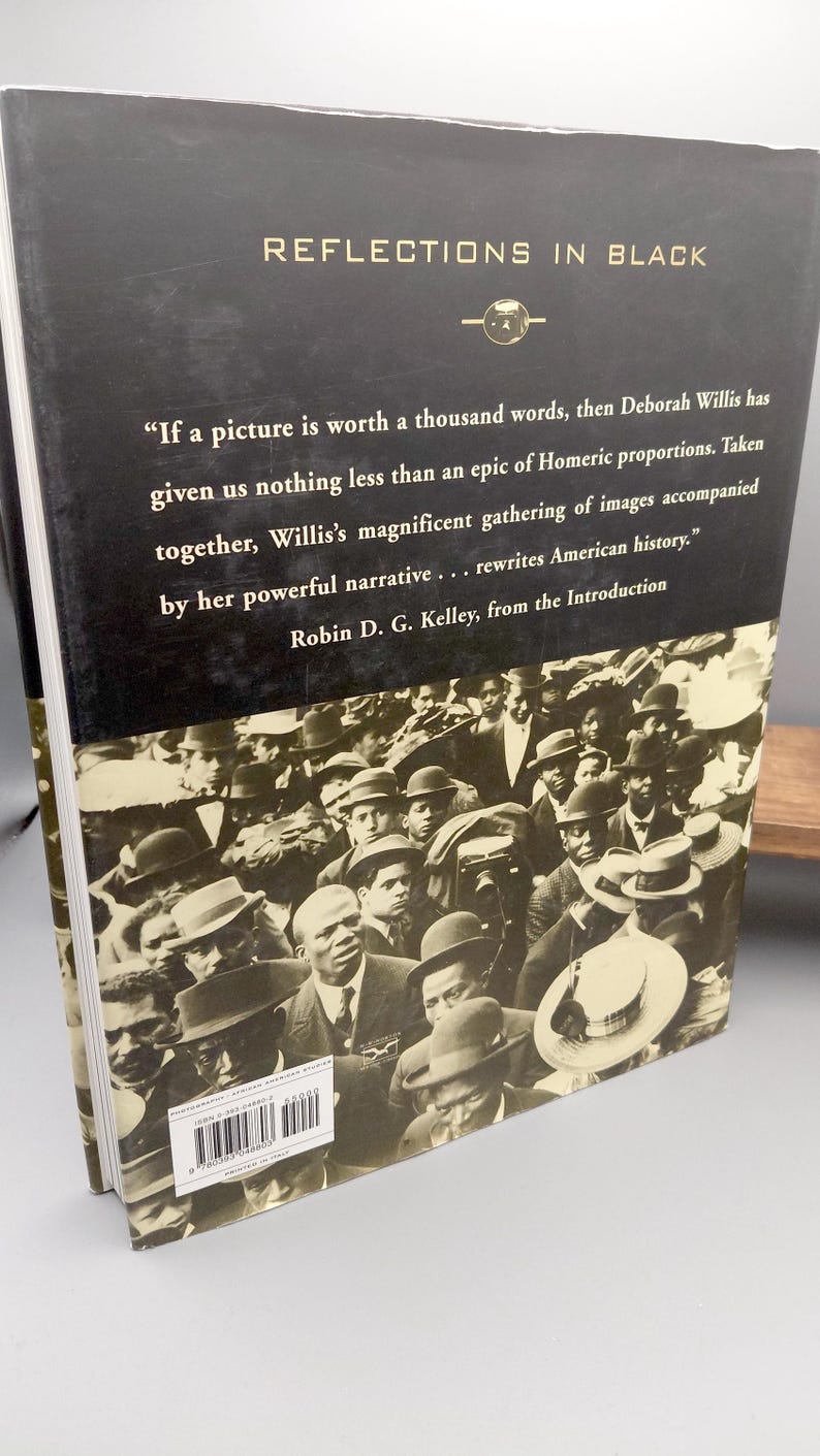Puede incluir: Un libro de tapa dura titulado "REFLECTIONS IN BLACK" con una cubierta negra y una fotograf&iacute;a en tonos sepia de una multitud. El libro incluye una cita sobre el poder de las im&aacute;genes y la reescritura de la historia estadounidense.