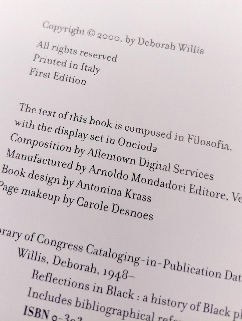 Puede incluir: Primer plano de una p&aacute;gina de libro con texto. El texto incluye informaci&oacute;n de derechos de autor, el nombre del autor y detalles sobre la producci&oacute;n del libro, como la imprenta y la fuente utilizada. El libro se titula "Reflections in Black".