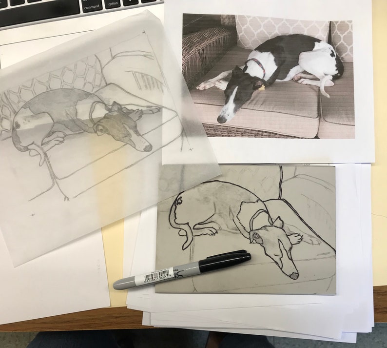 K&ouml;nnte beinhalten: Ein schwarz-wei&szlig;er Hund liegt auf einem gemusterten Kissen. Der Hund ist mit schwarzer Tinte auf einem wei&szlig;en Blatt Papier umrandet. Ein schwarzer Marker liegt auf einer grauen Oberfl&auml;che.