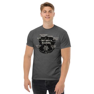 Op de afbeelding: Een donkergrijs gemêleerd T-shirt met korte mouwen en een centrale zwarte afbeelding met witte tekst: This shirt is decodable, omringd door taalkundige aantekeningen zoals Closed Syllable, Digraphs, r-controlled en Latijnse wortels.