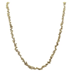 May include: A gold-colored necklace featuring a delicate design of clustered beads. The necklace is composed of small, round beads that are closely arranged, creating a textured and elegant appearance. The necklace is displayed against a white background.