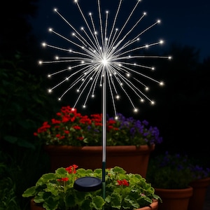 May include: A solar-powered garden light shaped like a burst of stars. The light has many thin, radiating wires with small, bright white lights at the ends. It is placed in a terracotta pot with red and purple flowers, against a dark night sky.
