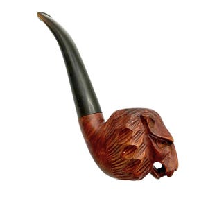 May include: A carved wooden tobacco pipe with a dark brown stem and a bowl shaped like a lion's head. The pipe is made of reddish-brown wood with detailed carving.