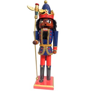 Puede incluir: Figura de cascanueces de madera con uniforme real. La figura tiene tez oscura, cabello negro y bigote. Viste una chaqueta azul con adornos dorados, pantalones rojos y botas negras. Sostiene un bastón dorado y se apoya sobre una base roja.