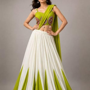 May include: A two-piece ensemble featuring a lime green sleeveless crop top with intricate circular embroidery and white tassel accents, paired with a floor-length white skirt featuring wide lime green triangular panels at the hem.
