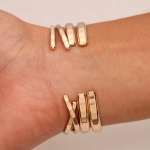 May include: Gold-toned bracelet with a hammered finish, featuring multiple bands that wrap around the wrist.