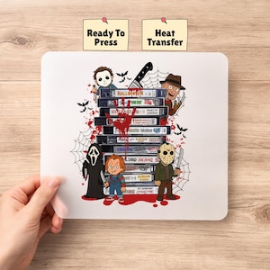 May include: A rectangular heat transfer sheet featuring a stack of horror movie VHS tapes surrounded by cartoon characters including Michael Myers, Freddy Krueger, Ghostface, Chucky, and Jason Voorhees, with red blood splatters and spider webs.