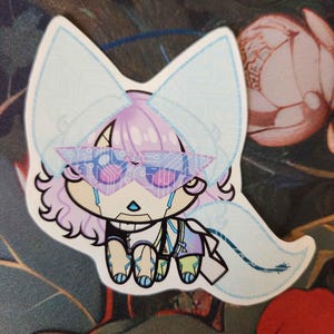 May include: A sticker featuring a stylized, crying fox-like character with light purple hair and futuristic glasses. The character has large, light blue ears and a matching tail. The design incorporates circuit board patterns and a color palette of blue, purple, and black.