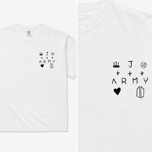 Op de afbeelding: Een wit T-shirt met korte mouwen en een kleine zwarte afbeelding op de linkerborst. Het ontwerp bevat een kroon, de letter J, een knipogend gezicht, plustekens, het woord ARMY, een hartje en een geometrisch logo als een schild.