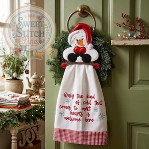 May include: A white Christmas-themed hand towel with a snowman design hanging on a green door. The towel has a red and white checkered border and the text "Only the kind of cold that comes to melt hearts is welcome here."