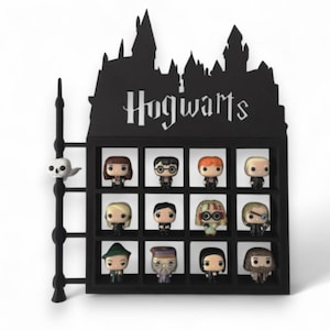 May include: Black display shelf with the word "Hogwarts" and a silhouette of a castle. The shelf holds twelve character figurines. A wand and a small skull are on the left side. The shelf is a decorative item for fans.