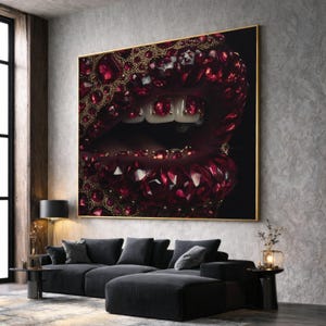 Puede incluir: Obra de arte enmarcada de gran tamaño que presenta un primer plano de una boca adornada con gemas de color rojo rubí y detalles dorados. La boca abierta revela dientes de oro. La obra se exhibe en un salón moderno con un sofá negro y una ventana grande.