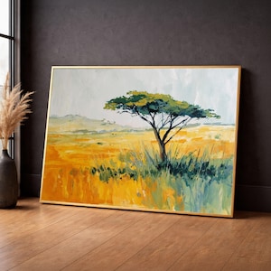 May include: An abstract landscape painting featuring a lone tree with a green canopy and a dark trunk, set against a yellow and green field. The artwork is framed in a gold-colored frame, evoking a sense of the African savanna.