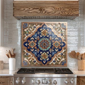 May include: A decorative kitchen backsplash with a copper frame and a detailed floral design in shades of blue, orange, and white. The backsplash is mounted above a stainless steel stove.