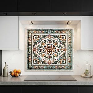 May include: A square decorative wall tile featuring a symmetrical floral mandala pattern in shades of teal, orange, and white. The design is enclosed within a multi-layered border of intricate scrollwork and geometric shapes, creating a detailed mosaic.