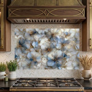 May include: A kitchen backsplash panel featuring a dense, layered floral pattern in shades of soft blue, cream, and white, accented with delicate gold-toned veining throughout the petals, positioned behind a stainless steel gas stove.