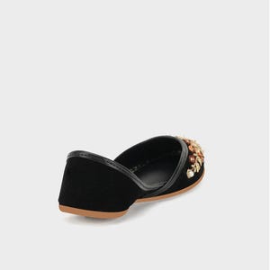 May include: Black velvet flat shoe with a decorative floral embellishment in shades of gold, brown, and cream. The shoe has a leather trim and a tan sole. This elegant shoe is perfect for special occasions.