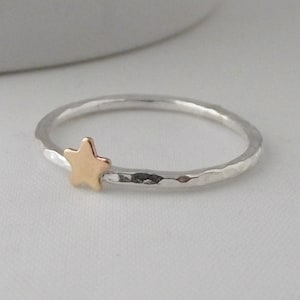 May include: A silver hammered ring with a gold star accent. The ring is simple and delicate.