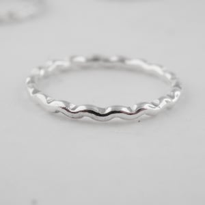 May include: A silver ring with a wavy, textured band.