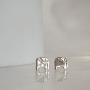 May include: A pair of silver elephant stud earrings. The earrings are small and delicate, and they are perfect for everyday wear.