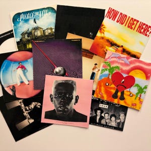 May include: A collection of vinyl record album covers, featuring diverse artwork and band names. The covers showcase various colors and designs, including a pink cover with a portrait, a cover with a red heart, and a cover with a beach scene.