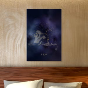 Puede incluir: Una impresión artística enmarcada que representa la constelación de Leo. La obra de arte muestra una silueta de león y líneas de constelación doradas sobre un fondo azul oscuro y púrpura. La palabra "LEO" está impresa en la parte inferior.