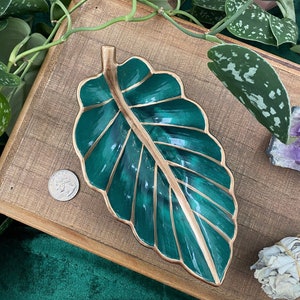 May include: A green leaf-shaped dish with gold trim. The dish is made of ceramic and has a glossy finish.