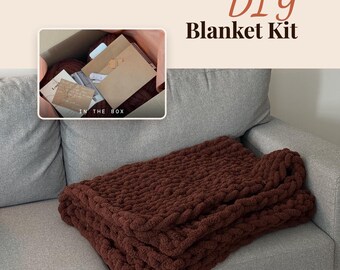 May include: A DIY Blanket Kit featuring a dark brown chunky knit blanket and an inset box containing craft supplies, a brown envelope, and a card with text. The text "DIY Blanket Kit" and "IN THE BOX" are visible in the image.