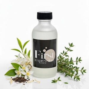 May include: A frosted glass bottle with a black cap and a black label that reads "First Impression Scents". The bottle is surrounded by white flowers, green leaves, and sprigs of thyme. The bottle contains a clear liquid.