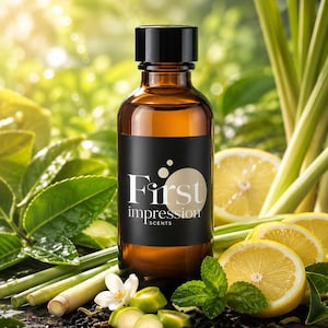 May include: An amber glass bottle with a black cap and a black label featuring the text First impression SCENTS. The bottle is surrounded by fresh lemongrass stalks, sliced yellow lemons, green mint leaves, and a small white flower.