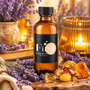 Puede incluir: Una botella de vidrio ámbar con tapa negra y una etiqueta negra con el texto blanco First impression SCENTS. La botella está rodeada de ramas de lavanda morada, varias piedras preciosas de color naranja translúcido y una vela encendida en un vaso.
