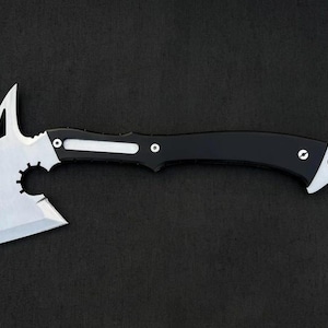 以下が含まれることがあります： 黒い柄と銀色の刃が付いたタクティカル・トマホーク・アックス。 刃は、尖った上部、円形の切り欠き、鋭いエッジを備えたユニークなデザインです。 ハンドルには白いアクセントがあり、リベットで固定されています。