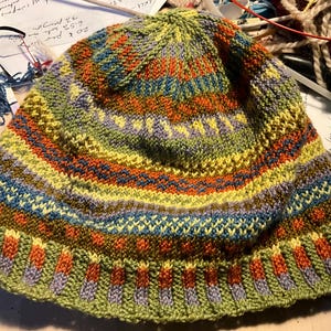 Puede incluir: Un gorro tejido a mano con un colorido dise&ntilde;o a rayas. El gorro presenta bandas verdes, amarillas, naranjas, azules y moradas. Hecho de hilo suave, es perfecto para los d&iacute;as fr&iacute;os.