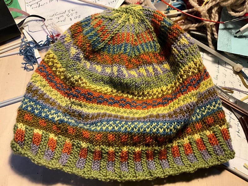 Puede incluir: Un gorro tejido a mano con un colorido dise&ntilde;o a rayas. El gorro presenta bandas verdes, amarillas, naranjas, azules y moradas. Hecho de hilo suave, es perfecto para los d&iacute;as fr&iacute;os.