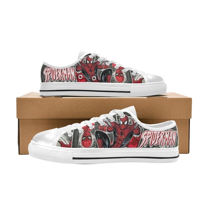 May include: Low-top sneakers featuring a white rubber toe cap, white laces, and a graphic print of the comic book character Spider-Man in red and black. The side panels display the text Spider-Man in a stylized font against a comic book background.