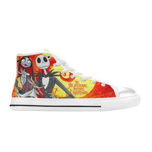 May include: A white high-top sneaker featuring a vibrant graphic print of Jack Skellington, Sally, and Zero from The Nightmare Before Christmas. The design includes a bright yellow moon, orange background, and white laces with a white rubber sole.