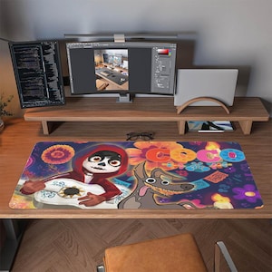 May include: A rectangular Coco-themed desk mat featuring Miguel playing a guitar and Dante the dog. The mat has a colorful design with the word "Coco" in large, stylized letters. The mat is on a wooden desk with computer monitors.