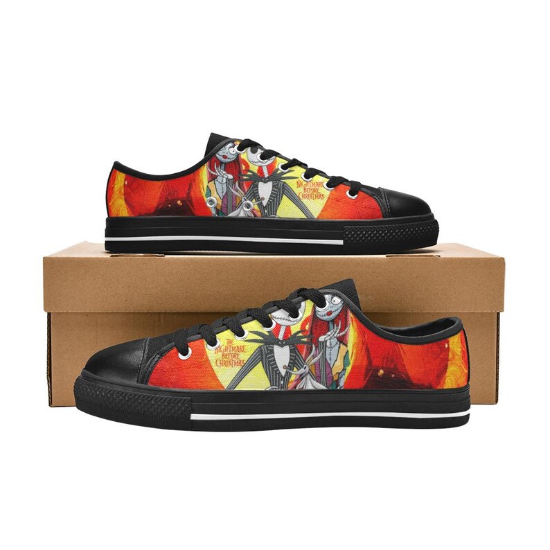 May include: Low-top trainers featuring a black toe cap, black laces, and a vibrant graphic print of Jack Skellington, Sally, and Zero from The Nightmare Before Christmas against a bright yellow and orange moonlit background with the movie title.