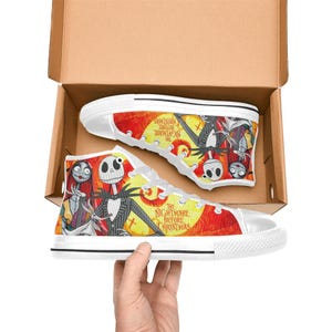 May include: High-top canvas sneakers featuring a vibrant print of Jack Skellington, Sally, and Zero from The Nightmare Before Christmas. The design includes a yellow moon, red background, and the movie title text on white rubber soles.