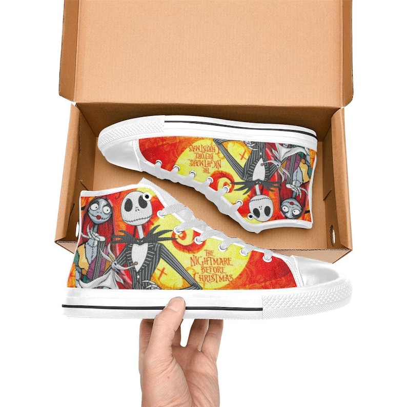 May include: High-top canvas sneakers featuring a vibrant print of Jack Skellington, Sally, and Zero from The Nightmare Before Christmas. The design includes a yellow moon, red background, and the movie title text on white rubber soles.