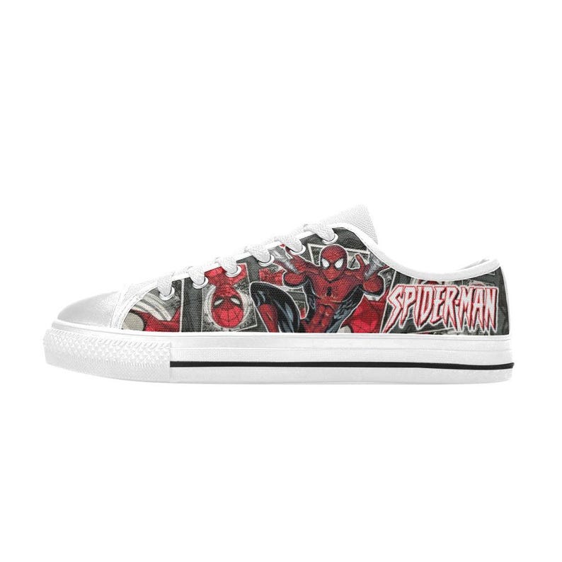 May include: A low-top sneaker featuring a comic book print of Spider-Man in red and blue against a black and white background. The shoe has white laces, a white rubber toe cap, and a white sole with a thin black stripe. The text SPIDERMAN is visible.